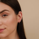 Model wears dainty rainbow sapphire huggie earring