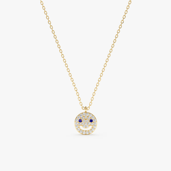 Solid gold happy face pendant with diamond smile and blue sapphire eyes on a gold chain.