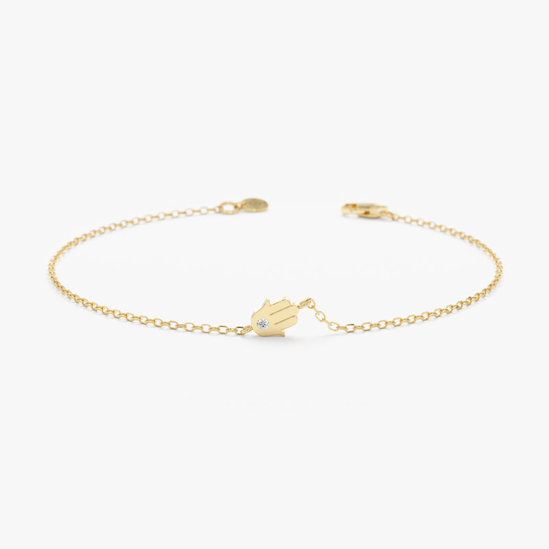 Sideways hamsa bracelet with solitaire diamond in solid gold.