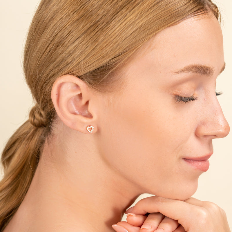 Model wears diamond lined heart shape stud earrings for her