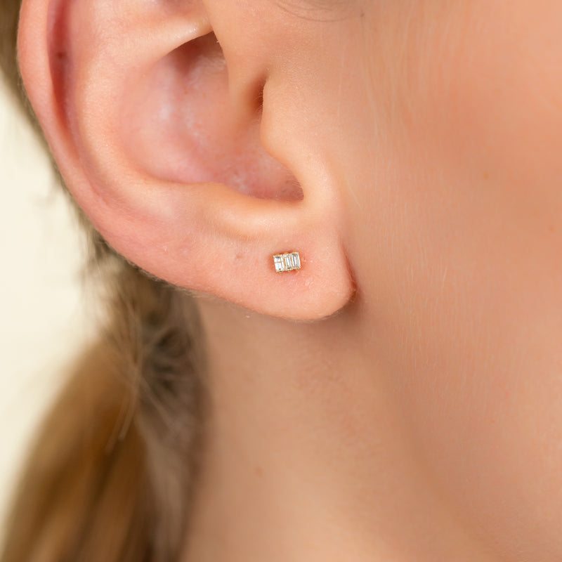 Model wears dainty solid 14k gold triple baguette diamond studs for her