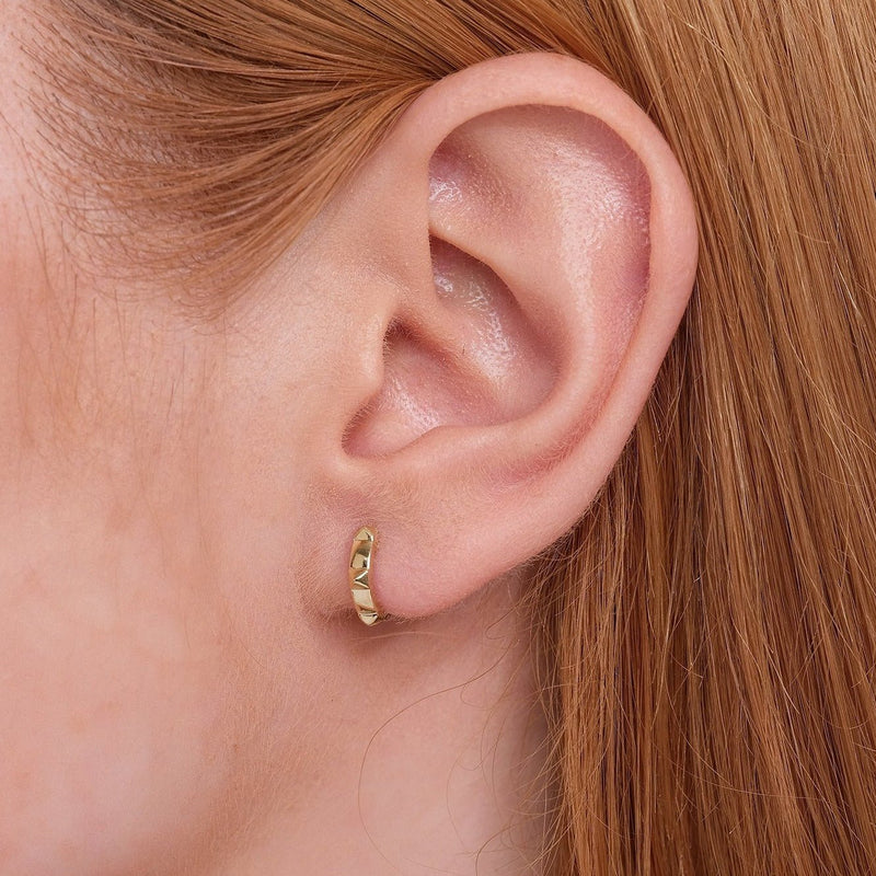 Model wears solid 14k handcrafted gold pyramid spike design hoop huggie. 